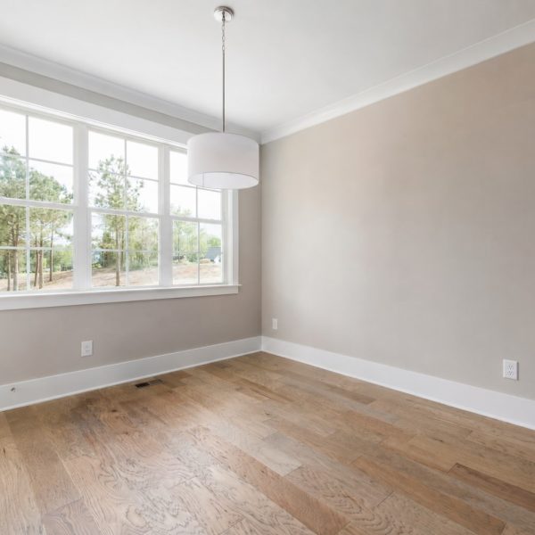 Hardwood floor with subtle water damage, staining, and mild cupping near a window